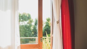 A bedroom with a bed, a window with curtains, and a view of greenery outside. - Sonho Da Serra Pousada (Bento Gonçalves)
