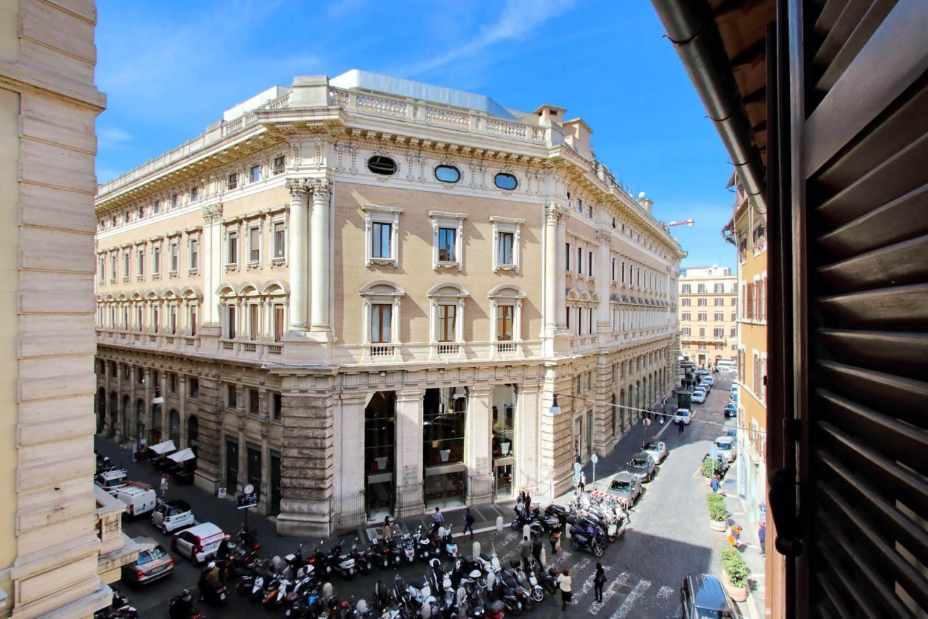 A historic building with classical architecture, large windows, and a busy street below.