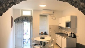 A compact kitchen with white cabinets, a built-in microwave, and a dining area with a round table and chairs.