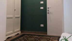 A hallway with a green wall, a white door, and a white wardrobe.