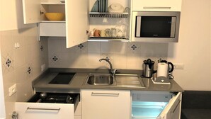 A compact kitchen with a microwave, sink, and a built-in oven.