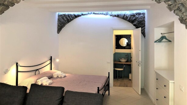 A bedroom with a bed, a dresser, and a bathroom with a sink and mirror.