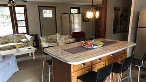 A compact kitchen with a central island, bar stools, a dining area with a sofa, and a ceiling fan. - Winter mtn views 2 min. to center, fireplace: Monthly rentals welcome! (Columbus)