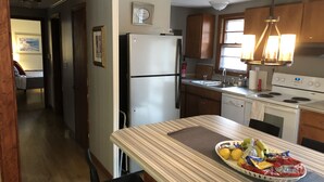 A kitchen with a refrigerator, stove, and a dining area with a table set for two. - Winter mtn views 2 min. to center, fireplace: Monthly rentals welcome! (Columbus)