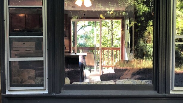 A view through a window with a ceiling fan, a wooden deck, and a stone fireplace. - Winter mtn views 2 min. to center, fireplace: Monthly rentals welcome! (Columbus)