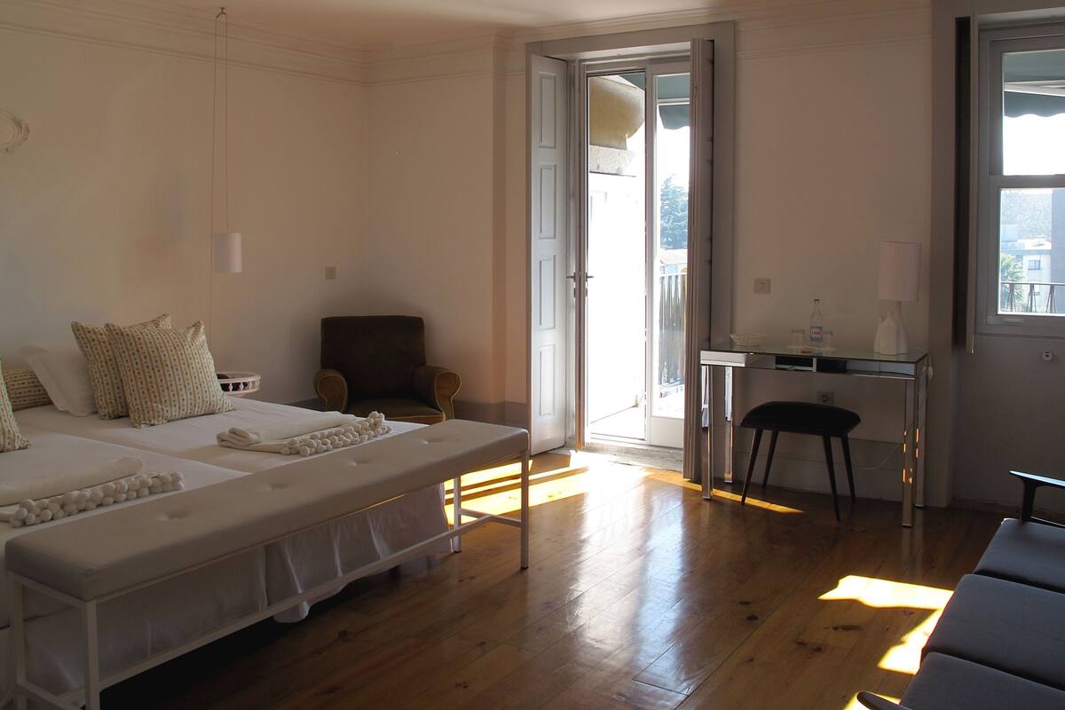 Un dormitorio con cama, una silla, un escritorio y una ventana.