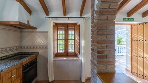 Een keuken met een raam, houten balken, een bakstenen muur en een bordje waarop 'SALIDA' staat.