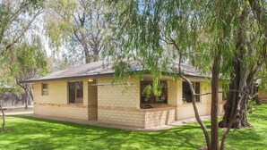 A single-story brick house with a flat roof, a front porch, and a small attached garage. - Siesta Park Holiday Resort (Busselton)