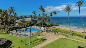 A resort with a swimming pool, beach, and palm trees.