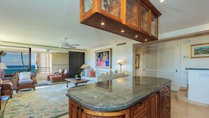 A spacious living area with a large island counter, a dining area, and a view of the ocean.
