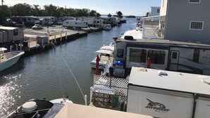 A marina with RVs docked along a narrow waterway, surrounded by trees and a building with a white facade. - *Snowbirds Paradise* (Marathon)