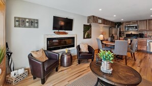 A modern living room with a fireplace, leather sofas, a coffee table, and a TV.