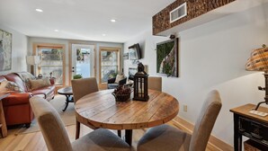 A cozy living room with a wooden dining table, comfortable seating, and a television.
