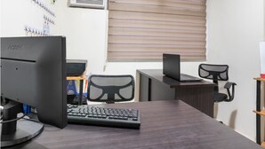 A modern office with a desk, computer, and chairs. - OYO 474 Nizami Condotel (Mandaluyong)