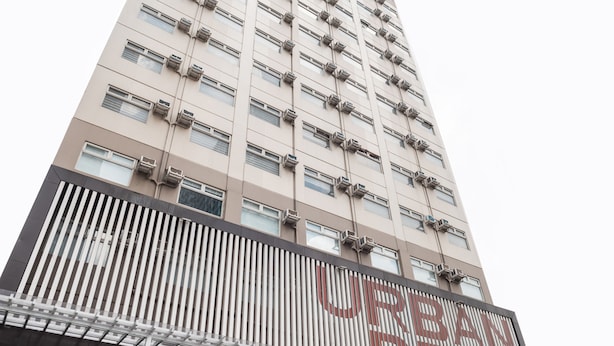 A multi-story hotel with a modern facade, large windows, and a prominent sign with Chinese characters. - OYO 474 Nizami Condotel (Mandaluyong)