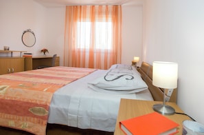 A hotel room with a bed, a desk, a chair, a lamp, and a window with curtains. - Apartment Ileora (Split)