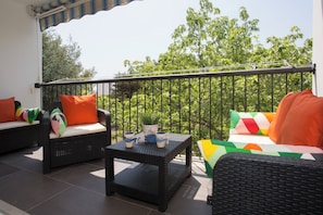 A balcony with wicker furniture, a small table, and a potted plant. - Apartment Ileora (Split)