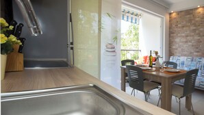 A modern kitchen with a stainless steel sink, a wooden countertop, and a dining area with a table and chairs. - Apartment Ileora (Split)