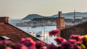 Una marina con barcos, una montaña al fondo y un edificio con chimenea.