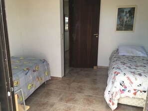 A room with two beds, each with a Minnie Mouse themed bedspread, a door, and a framed picture on the wall.