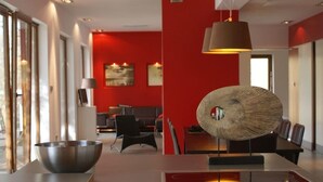 Een modern interieur met een rode accentmuur, een eethoek met een unieke geweven decoratie en een grote kom op een tafel.
