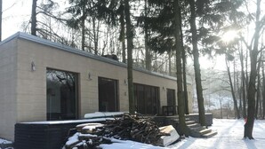 Een modern gebouw met grote ramen en een plat dak, omgeven door besneeuwde grond en bomen.
