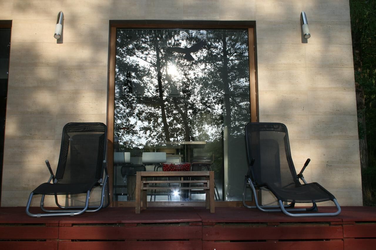 Two chairs facing a table with a view of trees through a glass door.