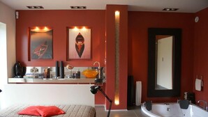 Een moderne badkamer met een groot bad, een wastafel met spiegel en kunst aan de wanden.
