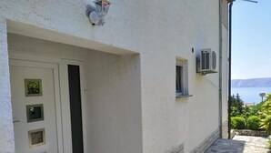 Een wit gebouw met een deur, een klein raam en een airconditioning.