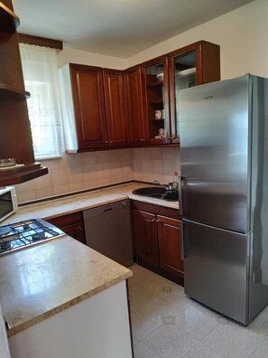 Una cocina con armarios de madera, un refrigerador de acero inoxidable, un microondas y un lavavajillas.