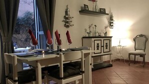 A dining area with a table set for two, a cabinet with decorative items, and a chair with a cushion. - Chic 'n Charme Trastevere Terrace (Roma)