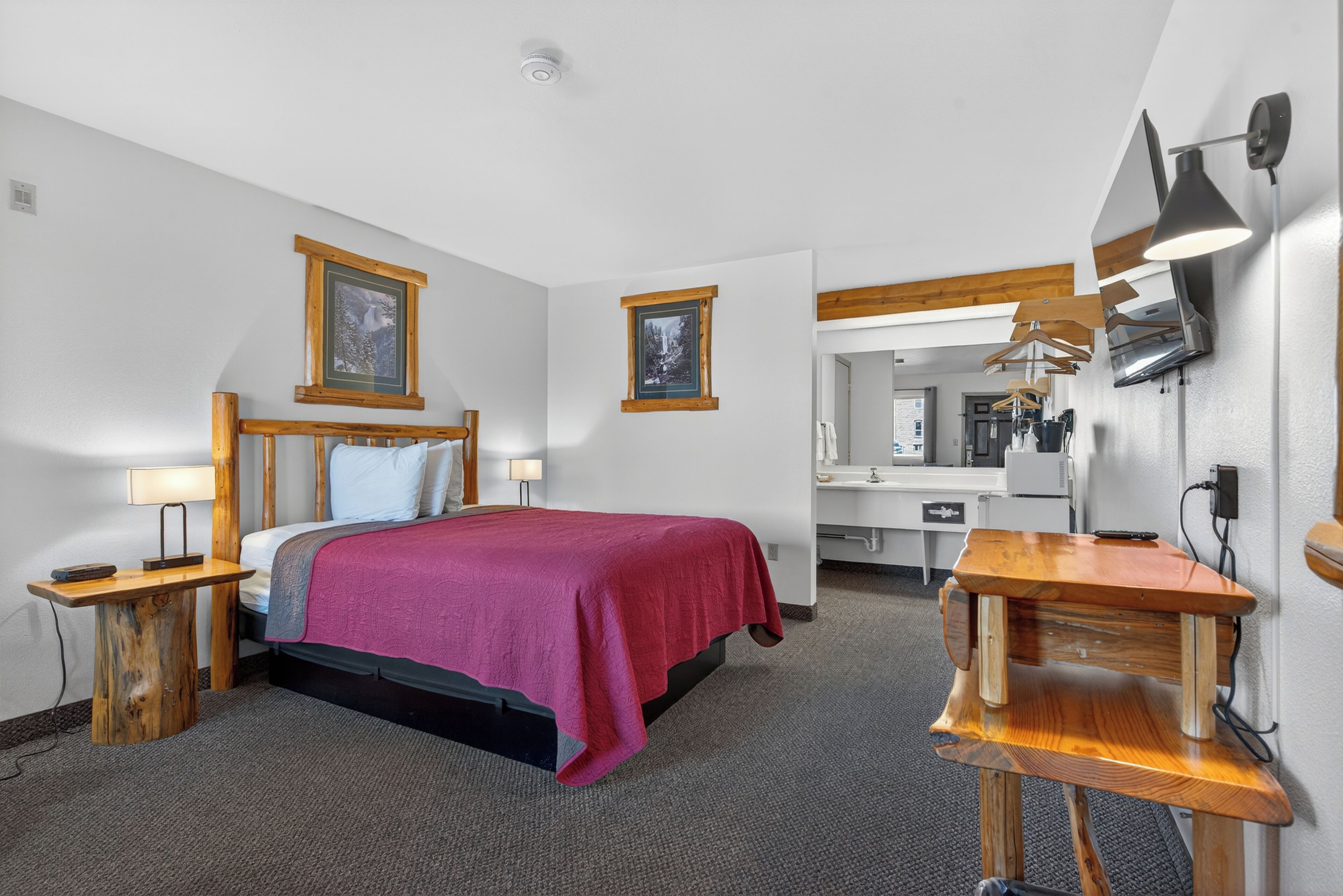 Une chambre d’hôtel comprenant un lit, des tables de chevet, un bureau, un miroir et un téléviseur.