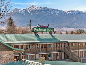 Un motel de dos pisos con techo verde y un letrero que dice 'Welcome to Ponderosa Motel'.