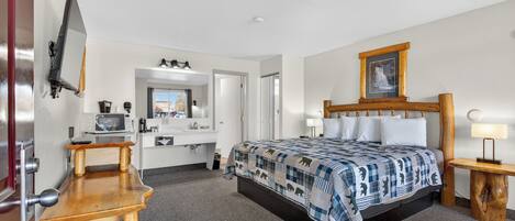 Ein Hotelzimmer mit Bett, Nachttisch, Lampe und Fernseher.