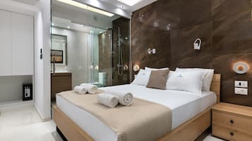 Habitación de hotel moderna con una cama grande, cabina de ducha de vidrio, mesita de noche de madera y armario empotrado.