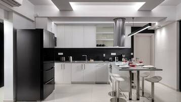 Una cocina moderna con un refrigerador negro, campana extractora de acero inoxidable y una zona de bar con taburetes.