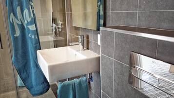 Un baño moderno con un lavabo blanco, un espejo y un perchero para toallas.