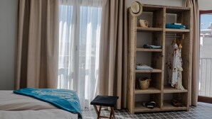 A hotel room with a bed, a wooden wardrobe, and a balcony with a view.