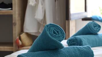 Una cama bien hecha con toallas azules enrolladas y una almohada blanca.