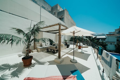 Una piscina al aire libre, sombrillas, sillones reclinables de piscina