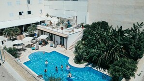 A rooftop pool area with a swimming pool, lounge chairs, and a covered seating area.