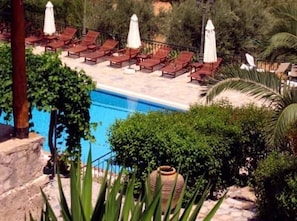 Relax by the serene pool surrounded by lush greenery and comfortable lounge chairs.