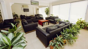 A spacious living room with black leather sofas, a coffee table, and multiple potted plants. - Ozalp Han Hotel (Ortaca)