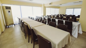 A conference room with multiple tables and chairs, large windows, and an air conditioning unit. - Ozalp Han Hotel (Ortaca)
