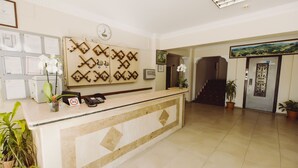 A reception area with a counter, framed certificates, a clock, and potted plants. - Ozalp Han Hotel (Ortaca)