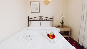 A neatly made bed with white linens, a bedside table with a lamp, and a framed picture on the wall. - Ozalp Han Hotel (Ortaca)