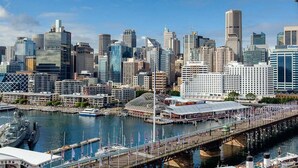 Un horizonte urbano con edificios modernos, un paseo marítimo y un puente.