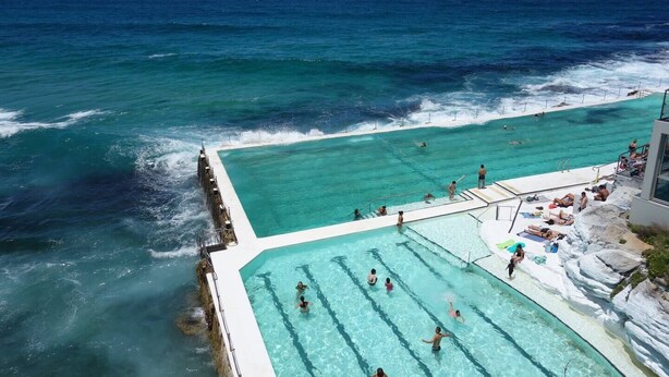 Una piscina junto a una costa rocosa con agua azul cristalina y vistas al océano.