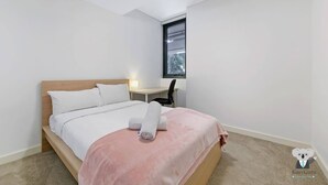 Un dormitorio con una cama, un escritorio y una ventana.