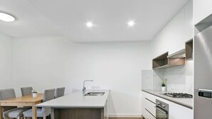 Una cocina moderna con una isla central, una mesa de comedor con sillas y electrodomésticos integrados.